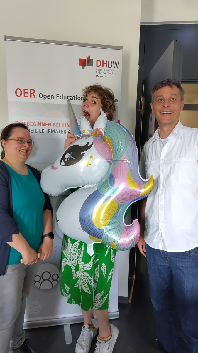 Gruppenbild vom TriebfedOERn Barcamp in Heilbronn: Einhorn-Maskottchen mit Silvia, Sonja und Jörg als Symbol für vernetzte Zusammenarbeit in der OER-Community.